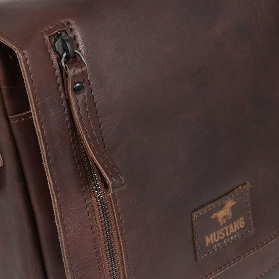 Detail van een donkerbruine leren tas met rits, drukknoop en Mustang logo.