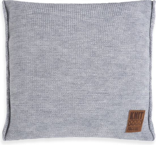 Een lichtgrijs, vierkant, gebreid sierkussen met een bruin leren label van Knit Factory.
