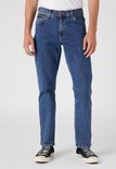 Man in blauwe jeans, van voren gezien, met bruin merklabel.