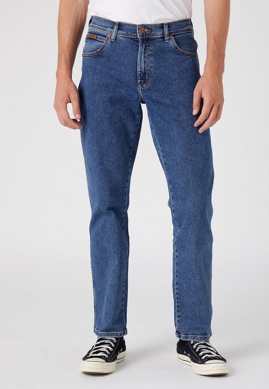 Man in blauwe jeans, van voren gezien, met bruin merklabel.