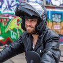 Man met baard en een matzwarte systeemhelm en zwarte leren jas.