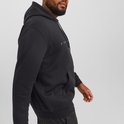 Man met baard en dreadlocks, zijaanzicht van een zwarte hoodie met Jack & Jones logo en donkere cargobroeken.