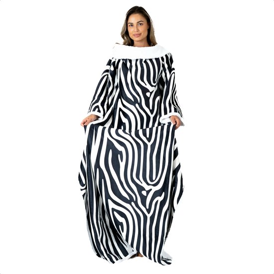 Vrouw in het midden van het beeld, staand en voorstellend een lange deken met mouwen, zebra-print en witte fleece kraag.