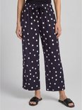 Onderlichaam van een model in een marineblauwe culotte met witte polkadotprint, wijde pijpen en strikceintuur.