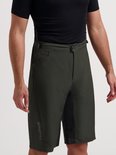 Model draagt een olijfgroene Rogelli MTB-fietsbroek met zwarte details en een zwarte bovenkant.