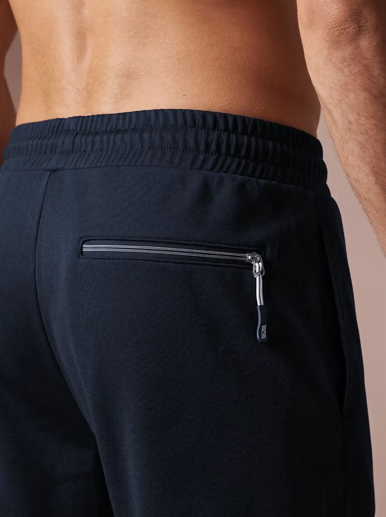 Close-up van marineblauwe sportshort met een ritszak aan de achterzijde, voorzien van een SJS-ritstrekker.