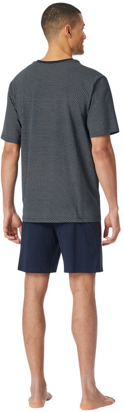 Man in nachtblauw pyjamashort met donkerblauw, wit geprint t-shirt met kleine ruitjes.