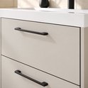 Detailopname van beige lades met strakke, zwarte handgrepen en een witte wastafelrand.