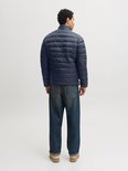 Achteraanzicht van het donkerblauwe, gewatteerde pufferjack gedragen met een jeans.