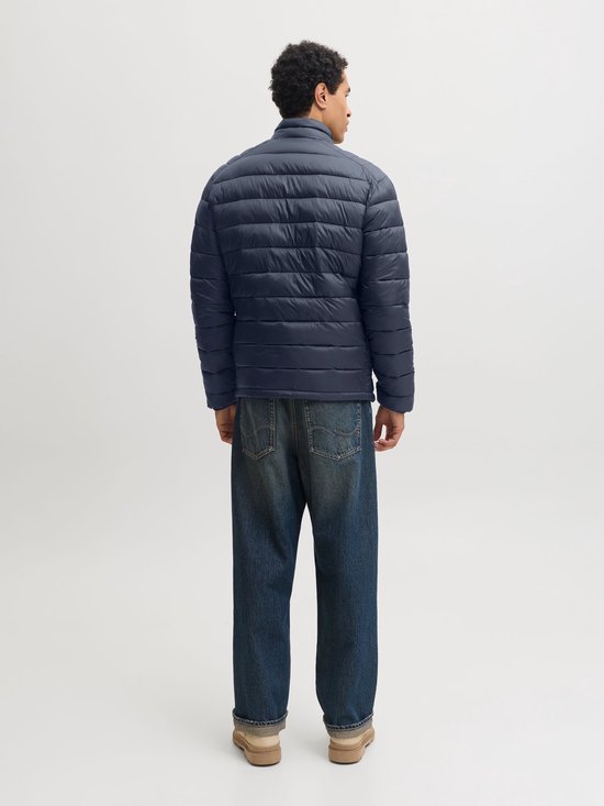 Achteraanzicht van het donkerblauwe, gewatteerde pufferjack gedragen met een jeans.