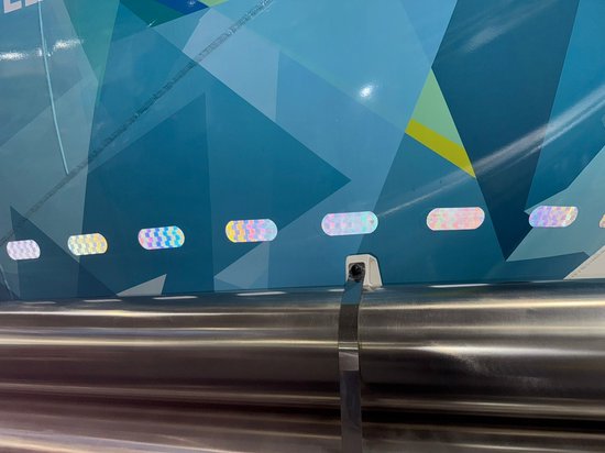 Rij met kleine, meerkleurige reflecterende stickers op een blauwe, geometrisch patronen achtergrond.