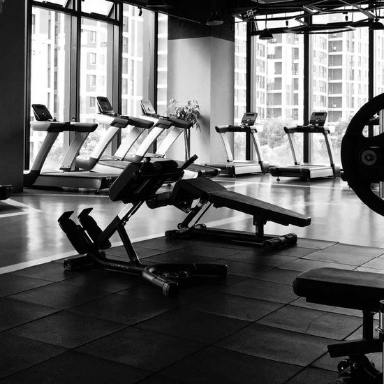 Zwart-wit overzicht van een moderne sportschool met Matrix-fitnessapparatuur, loopbanden en gewichtbanken.