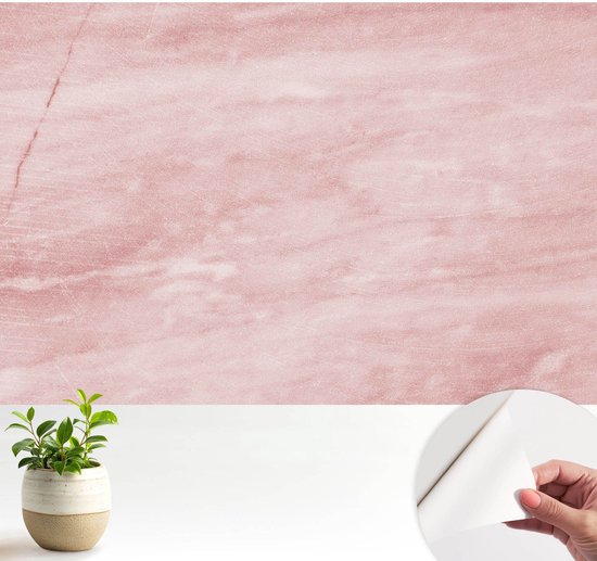 Zelfklevend roze vliesbehang met marmerpatroon, een kamerplant in een pot en een hand die de zelfklevende zijde laat zien.