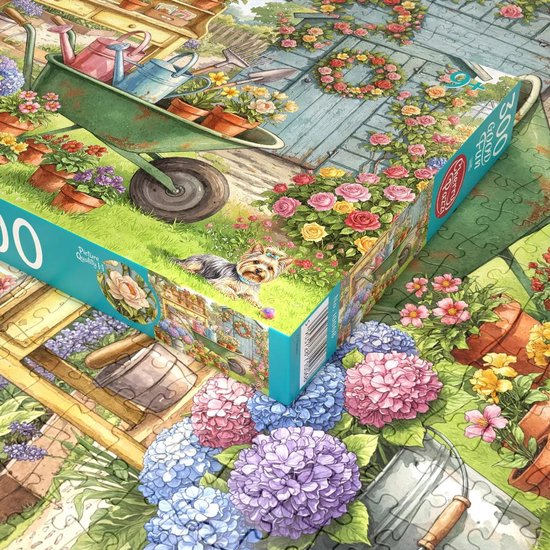 Detail van een 300-delige puzzel: een close-up van hortensia's, potten met bloemen, een kruiwagen en een Yorkshire Terriër in een tuin.