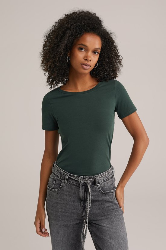 Model met donkergroen t-shirt met korte mouwen en grijze jeans met ceintuur.