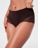 Close-up van een bruine Spanx Hi-Hipster met kanten zijpanelen en gladde stof bij de taille.