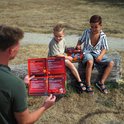 Man bekijkt opengevouwen 'KIDS BOX PLAY XXL' kaart, twee jongens zitten op boomstam.