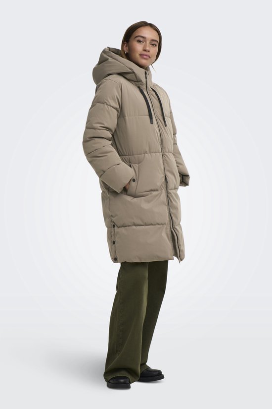 Model in lang, beige gewatteerd jack met capuchon, met zwarte trekkoorden en steekzakken.