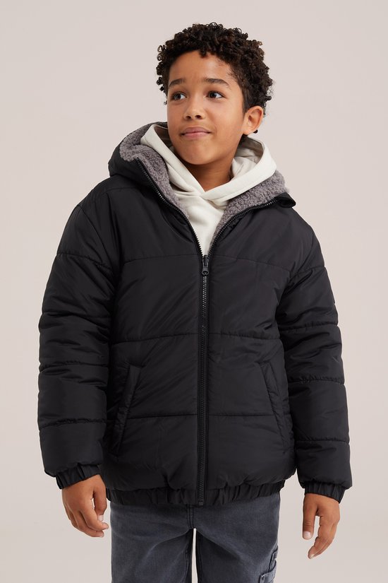 Jongen in zwarte jas met capuchon, beige hoodie eronder.