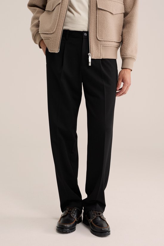 Man met beige jas en zwarte pantalon.