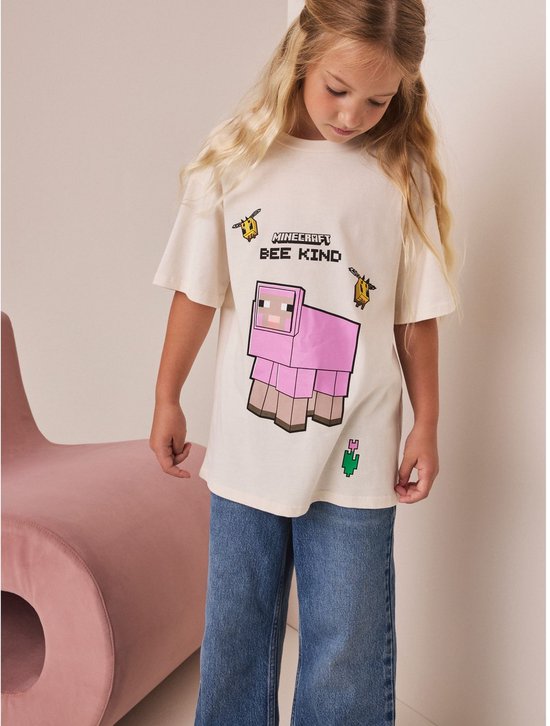 Crème oversized T-shirt met Minecraft print van een roze schaap en bijen, gedragen door een meisje.