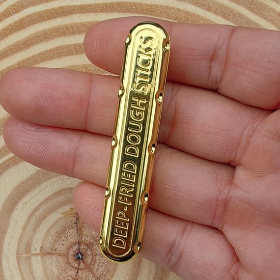 Gouden fidget speelgoed met de tekst "DEEP-FRIED DOUGH STICKS" in reliëf.
