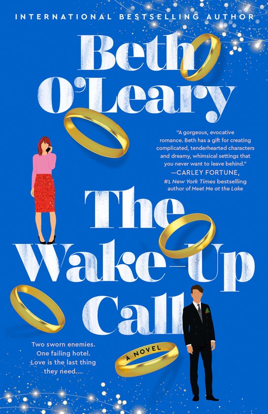 Boekcover 'The Wake-Up Call' van Beth O'Leary met een blauwe achtergrond, twee gouden trouwringen en een man en vrouw die elkaar aankijken.