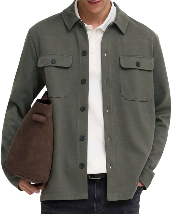 Close-up man met olijfgroene utility blouse, wit poloshirt en donkerbruine tas.
