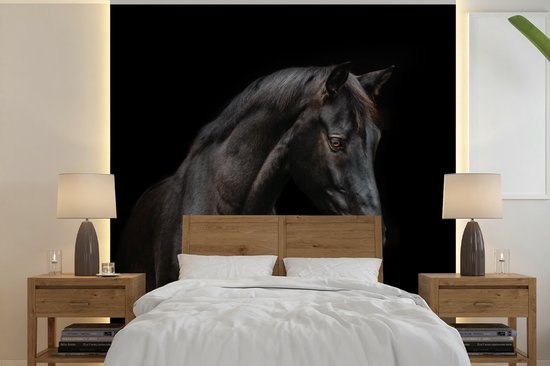 Fotobehang van een zwart paard achter een houten tweepersoonsbed met wit beddengoed en nachtkastjes.