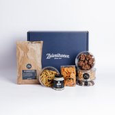 Een blauwe cadeauverpakking van Zuivelhoeve met daarin chips, dips, noten, koekjes en chocolade.