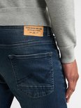 Close-up van de achterkant van een donkerblauwe jeans met leren label van Petrol Industries.