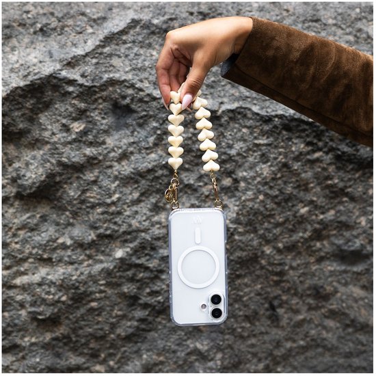 Een hand houdt een telefoonhoesje met lanyard adapter vast. De adapter is een koord van beige hartjes.