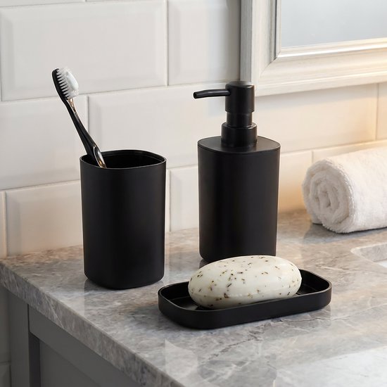 Set d'accessoires de salle de bain noirs comprenant un distributeur de savon, un gobelet avec une brosse à dents et un porte-savon avec un savon.