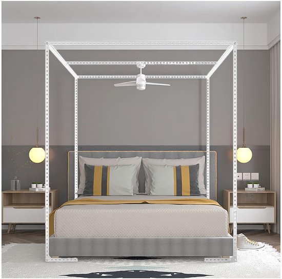 Wit hemelbedframe in een slaapkamer, boven een bed met gestreept kussen en gele deken.