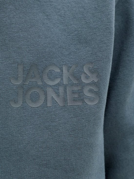 Close-up van het reliëf 'JACK & JONES' logo op de blauwgrijze stof van een hoodie.