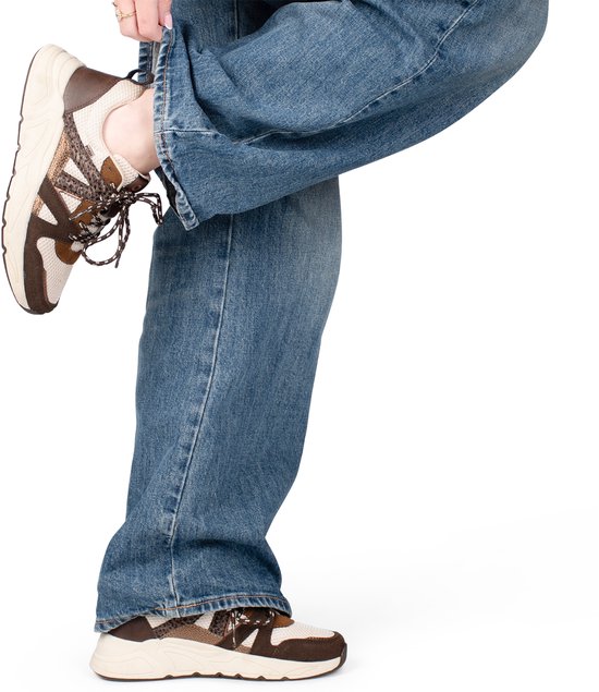 Dames met blauwe spijkerbroek en bruine sneakers met witte mesh en luipaardprint details.