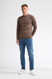 Volledige outfit van een man met een bruine gemêleerde trui, blauwe jeans en witte sneakers.