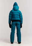 Meisje van achteren in een blauwe ski-jas, muts, broek en zwarte handschoenen. Zwarte band onderaan de jas.