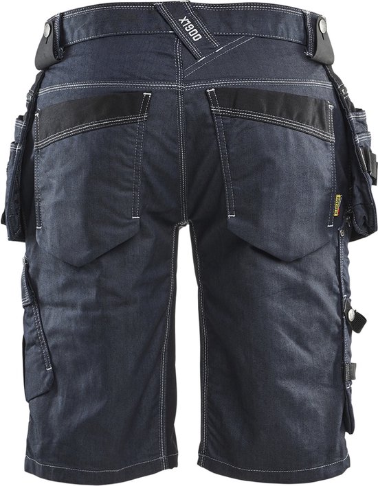 Achterkant van een donkerblauwe werkshort met het label 'X1900', riemlussen, zeven zakken en witte stiksels.