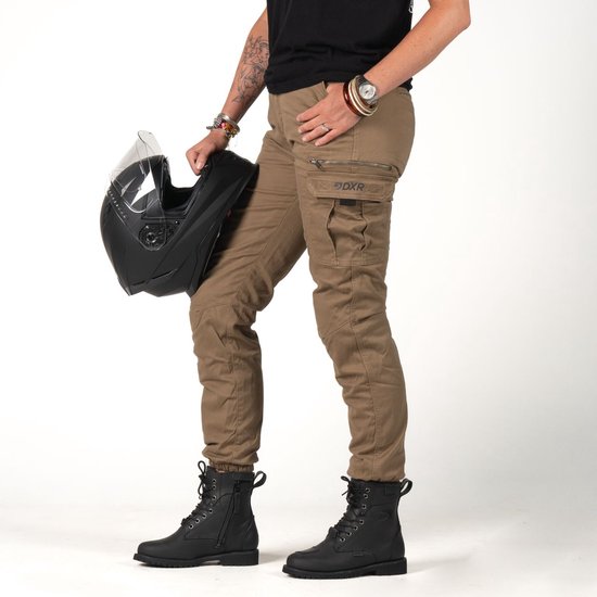 Model in bruine cargobroek, met ritszakken en 'DXR'-logo, en zwarte laarzen.