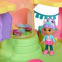 Gabby pop met blauwe jas, roze rok en paarse haren naast een roze huisje met vlinderdetails.