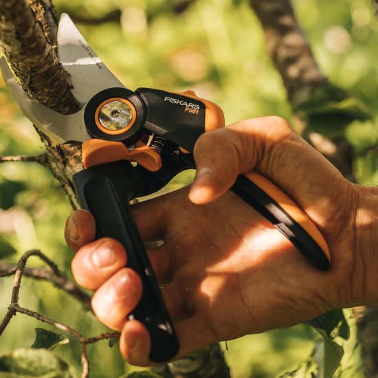 Fiskars P361 snoeischaar met oranje accenten, in een hand. Bypass mes met 'QUALITY SINCE 1849' tekst.