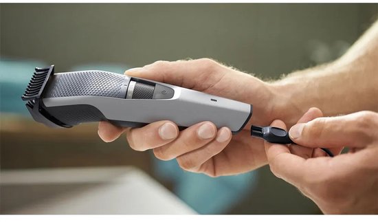 Handen verbinden de USB-oplaadkabel met een zilveren Philips baardtrimmer.