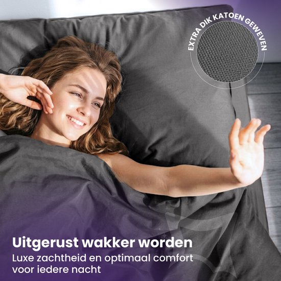 Vrouw ligt lachend onder een donkergrijs dekbedovertrek; extra dik geweven katoen.