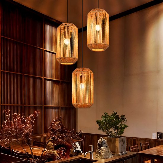 Drie hanglampen van gevlochten touw, cilindervormig, in een sfeervol restaurantinterieur.
