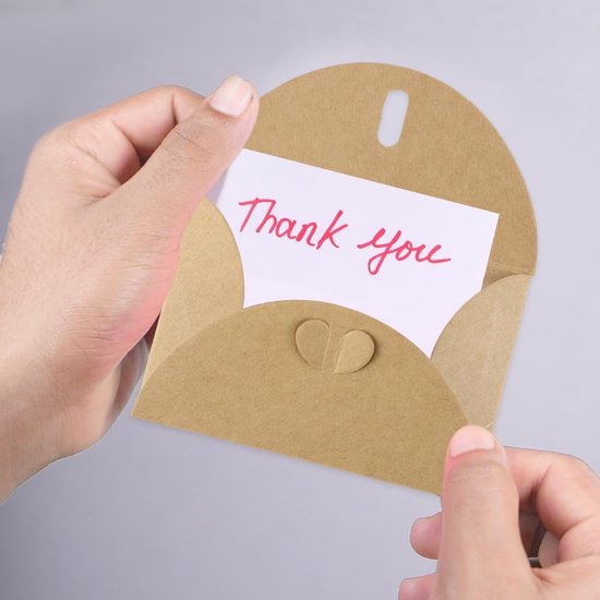 Handen houden een open bruine envelop vast met een wit kaartje waarop in het rood 'Thank you' staat.