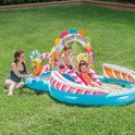 Een gezin geniet van het 'Candy Zone' speelbad met glijbaan in de tuin, met twee kinderen op de glijbaan en een vrouw zittend ernaast.