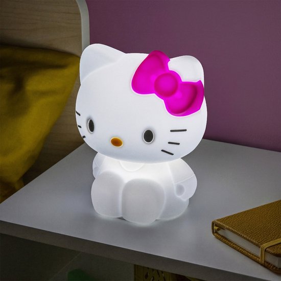 Une lampe en silicone Hello Kitty douce et lumineuse avec un nœud rose, assise sur une table de chevet.