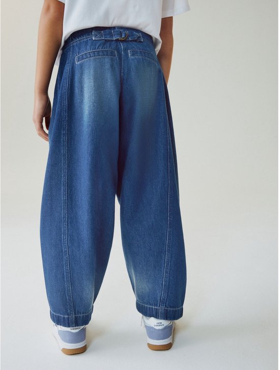 Meisje van achteren gezien, draagt wijde blauwe denim broek.