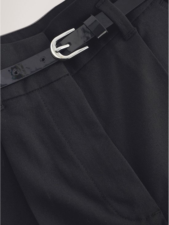 Zwarte wijde broek met glanzende zwarte riem en zilveren gesp.